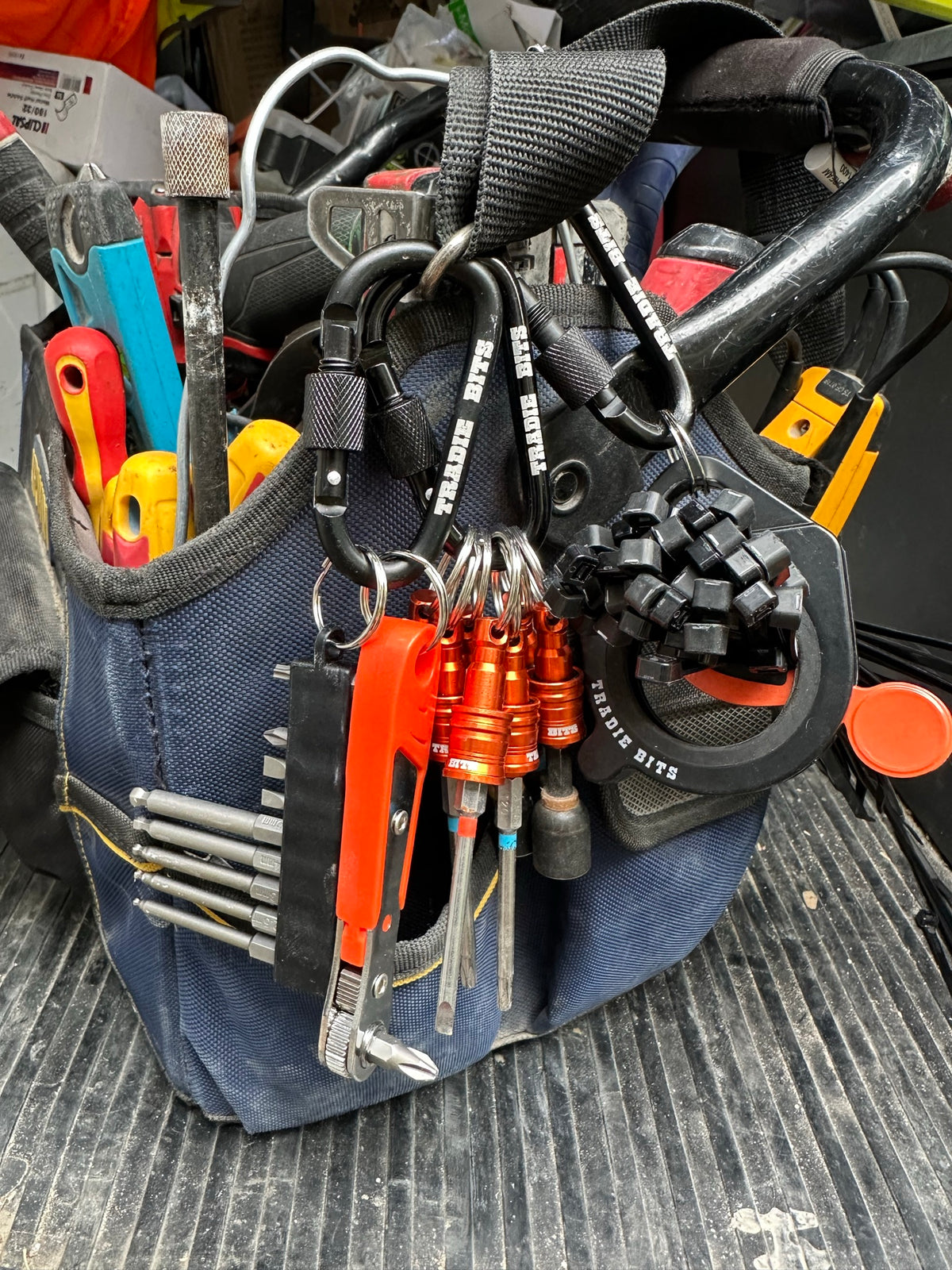 All three Smarter Not Harder Kit tools clipped to a tradie's tool bag